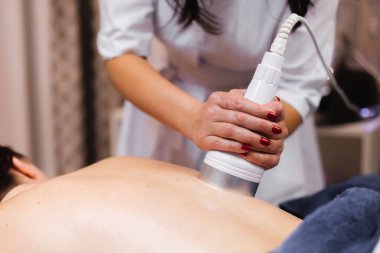 Spa salonundaki kız sırt ve boyun masajı yaptırıyor, kozmetoloji masasında uzanıyor, rahatlıyor ve bu süreçten zevk alıyor.