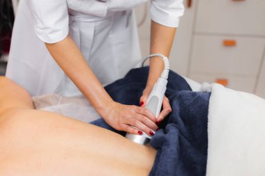 Spa salonundaki kız sırt ve boyun masajı yaptırıyor, kozmetoloji masasında uzanıyor, rahatlıyor ve bu süreçten zevk alıyor.