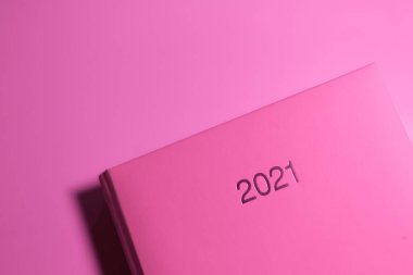 Pembe bir günlük defterinin kapağında 2021 yazılıydı. Pembe ışık, üst görünüm.