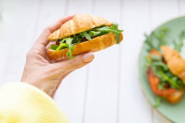 Elinde roka ve sebzeli kruvasan var.