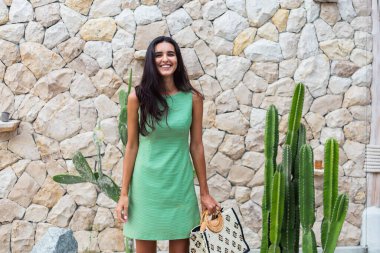 Zarif yeşil elbise içinde şık, mutlu, gülümseyen bir kadının portresi.