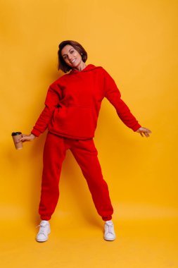 Mutlu, bronzlaşmış beyaz kadın portresi, modaya uygun, kırmızı yün kapüşon ve pantolon giyiyor.