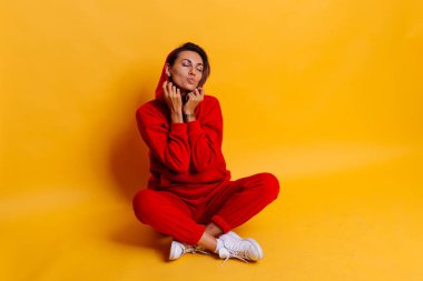 Mutlu, bronzlaşmış beyaz kadın portresi, modaya uygun, kırmızı yün kapüşon ve pantolon giyiyor.