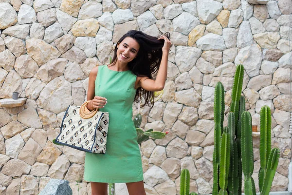 Zarif yeşil elbise içinde şık, mutlu, gülümseyen bir kadının portresi.