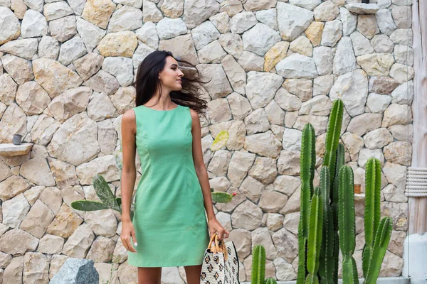 Zarif yeşil elbise içinde şık, mutlu, gülümseyen bir kadının portresi.