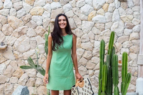 Zarif yeşil elbise içinde şık, mutlu, gülümseyen bir kadının portresi.