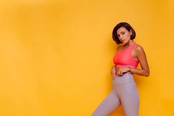 Spor ve yoga yaşam tarzı konsepti. Genç fit oldukça güçlü bir kadın spor kıyafetleri, şık bir bluz ve tayt giymiş.