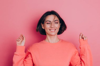 Pembe arka plan stüdyo resminde izole edilmiş 20 'li yaşlardaki komik genç kadın. İnsanlar yaşam tarzı kavramını hisseder. Kopyalama alanı oluşturun. Kafasını sallıyor dalgalı saçlarıyla