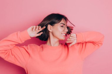 Pembe arka plan stüdyo resminde izole edilmiş 20 'li yaşlardaki komik genç kadın. İnsanlar yaşam tarzı kavramını hisseder. Kopyalama alanı oluşturun. Kafasını sallıyor dalgalı saçlarıyla