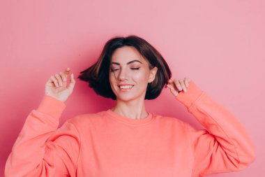 Pembe arka plan stüdyo resminde izole edilmiş 20 'li yaşlardaki komik genç kadın. İnsanlar yaşam tarzı kavramını hisseder. Kopyalama alanı oluşturun. Kafasını sallıyor dalgalı saçlarıyla