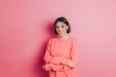 Güzel, gülümseyen esmer kadın modelinin portresi. Günlük şeftali rengi süveter, parlak makyaj ve pembe dudaklar.