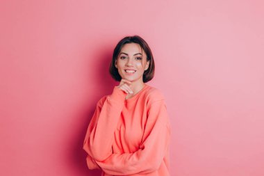 Güzel, gülümseyen esmer kadın modelinin portresi. Günlük şeftali rengi süveter, parlak makyaj ve pembe dudaklar.