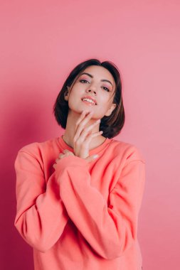 Güzel, gülümseyen esmer kadın modelinin portresi. Günlük şeftali rengi süveter, parlak makyaj ve pembe dudaklar.