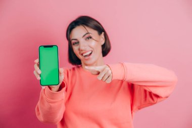 Şu cep telefonuna bak! Mutlu kadın işaretleri boş ekrana işaret ediyor, modern aletler gösteriyor, mutlu ve şaşırmış duygular..