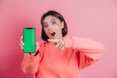 Şu cep telefonuna bak! Mutlu kadın işaretleri boş ekrana işaret ediyor, modern aletler gösteriyor, mutlu ve şaşırmış duygular..