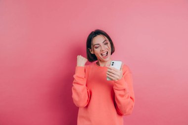 Heyecanlı genç bir kadın, akıllı telefona bakıp, cep telefonundan neşe içinde bağıran inanılmaz bir alışveriş uygulaması satışı mesajına hayran kaldı. 