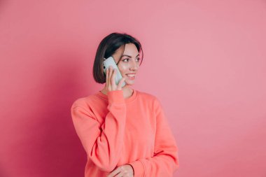 Pembe arka planda izole edilmiş akıllı telefondan konuşurken gülümseyen kadın fotoğrafı