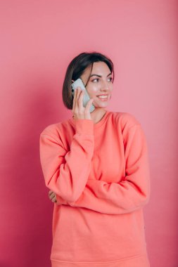Pembe arka planda izole edilmiş akıllı telefondan konuşurken gülümseyen kadın fotoğrafı