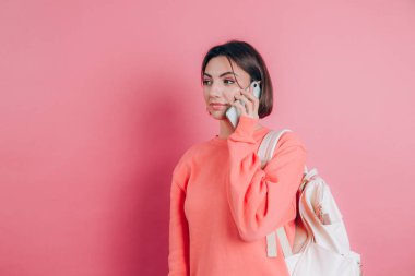 Pembe arka planda izole edilmiş akıllı telefondan konuşurken gülümseyen kadın fotoğrafı