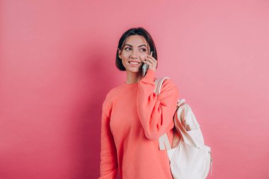 Pembe arka planda izole edilmiş akıllı telefondan konuşurken gülümseyen kadın fotoğrafı