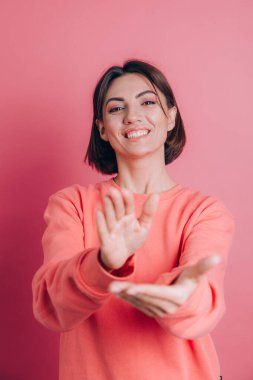 Arka planda rahat bir süveter giyen, alkışlayan mutlu ve neşeli, gururlu elleri bir arada tutan bir kadın.