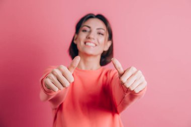 Arka planda sıradan bir süveter giyen kadın, olumlu bir jest yapmayı onaylıyor, gülümseyerek ve başarı için mutlu.