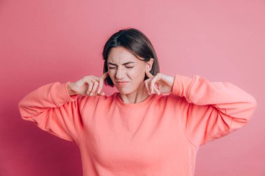 Arka planda süveter giyen kadın yüksek sesli müzik sesi için kulaklarını parmaklarıyla kapatıyor.. 