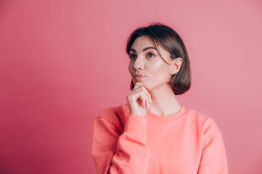 Arka planda sıradan bir süveter giyen bir kadın çene üstüne bir kadın soru soruyor, düşünceli bir yüz ifadesi var. Düşünceli bir yüzle gülümsüyor.