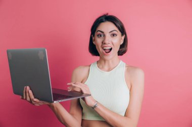 Pembe arka plandaki kadınlar çenelerini açık tutarlar dizüstü bilgisayarlarını tutarlar