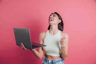 Pembe arka plandaki kadınlar diz üstü bilgisayarı tutuyor.