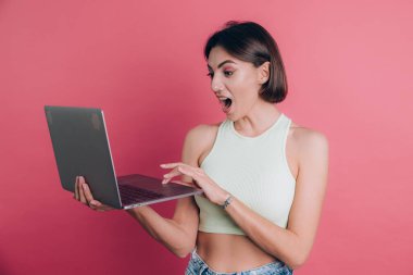 Pembe arka plandaki kadınlar çenelerini açık tutarlar dizüstü bilgisayarlarını tutarlar