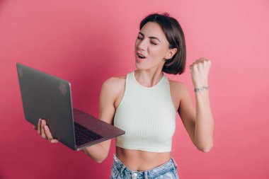 Pembe arka plandaki kadınlar diz üstü bilgisayarı tutuyor.