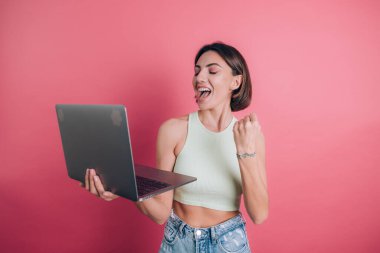 Pembe arka plandaki kadınlar diz üstü bilgisayarı tutuyor.