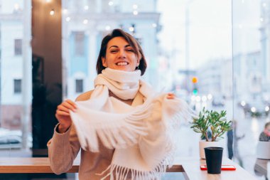 Sıcak bir kafede bir kız kendini bir fincan sıcak kahveyle ısıtıyor.