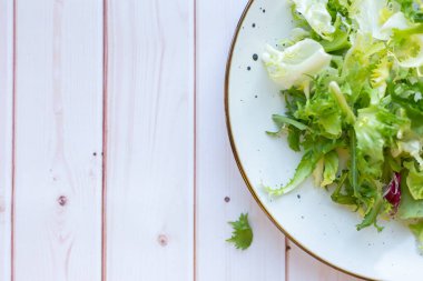 Ahşap zemin üzerinde taze salata ile beyaz seramik tabak