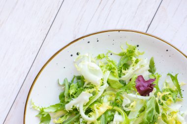 Ahşap zemin üzerinde taze salata ile beyaz seramik tabak