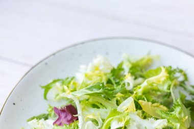 Ahşap zemin üzerinde taze salata ile beyaz seramik tabak