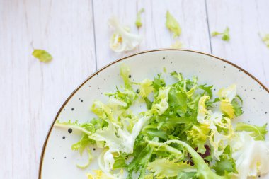 Ahşap zemin üzerinde taze salata ile beyaz seramik tabak