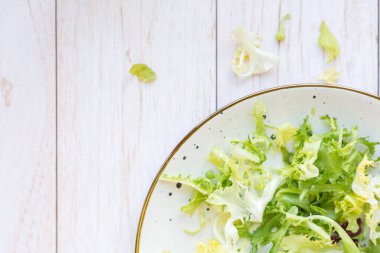 Ahşap zemin üzerinde taze salata ile beyaz seramik tabak