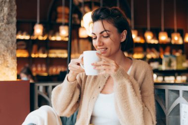 Bir kafede bir fincan sıcak kahve içen bir kız.