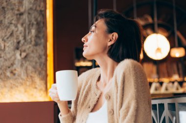 Bir kafede bir fincan sıcak kahve içen bir kız.