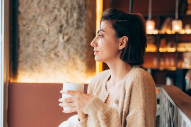 Bir kafede bir fincan sıcak kahve içen bir kız.