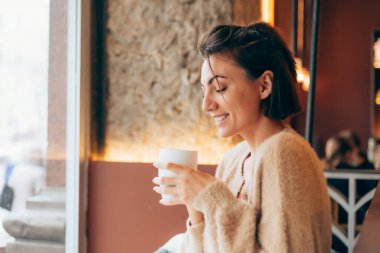 Bir kafede bir fincan sıcak kahve içen bir kız.