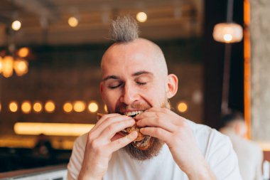 Bir kafede Avrupalı görünümlü vahşi bir adamın lezzetli bir sandviçi var.
