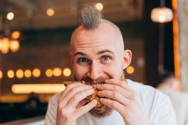 Bir kafede Avrupalı görünümlü vahşi bir adamın lezzetli bir sandviçi var.