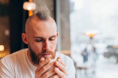 Sabahları bir kafede bir fincan sıcak kahveyle gezen vahşi Avrupalı bir adam.