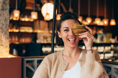 Kafede fıstıklı kruvasanla mutlu bir kadının portresi.