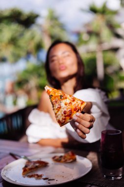 Asyalı güzel kadın güneşli bir günde pizza yiyor.