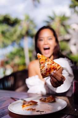 Asyalı güzel kadın güneşli bir günde pizza yiyor.