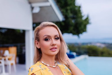 Parlak gece makyajlı, yaz sarısı elbise giyen güzel bir kadın.